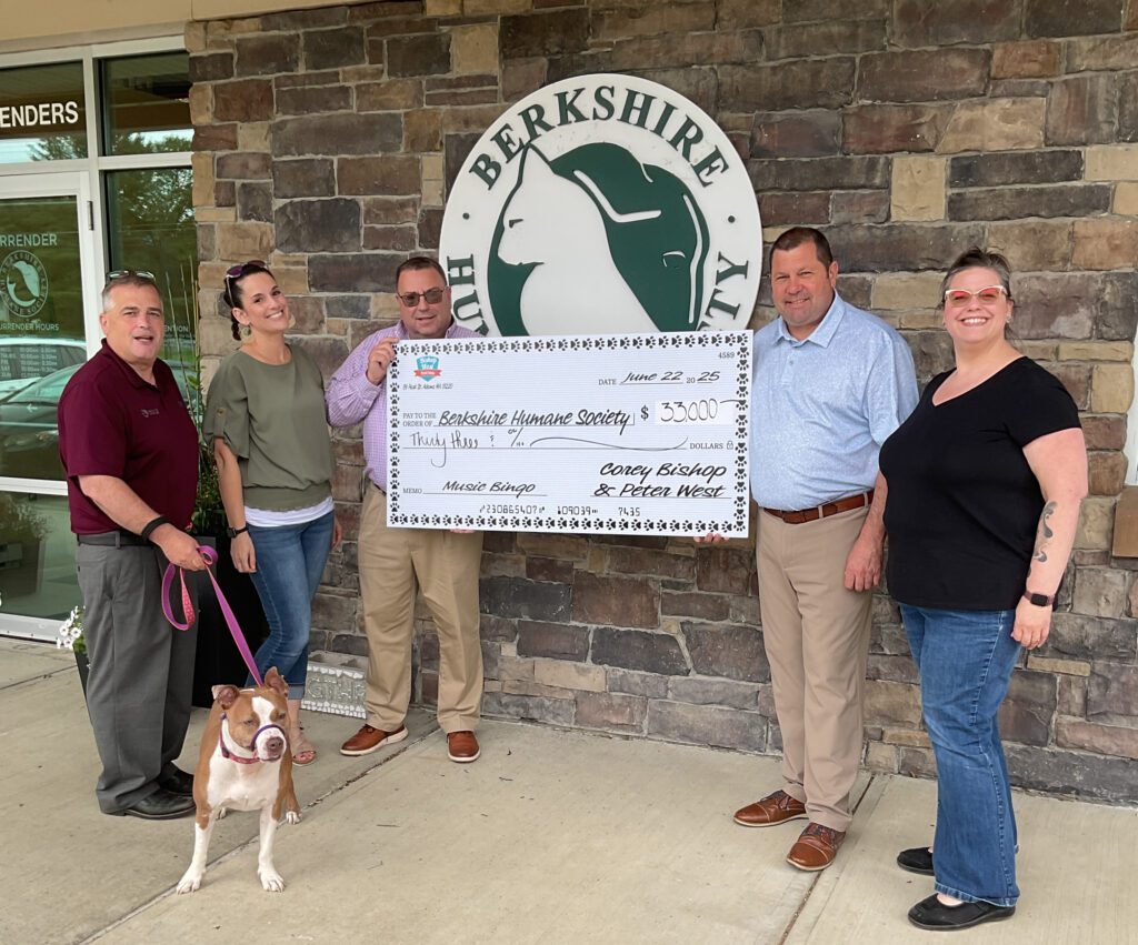 Three men, two women and a dog stand with a giant check to Berkshire Humane Society in the amount of $33,000